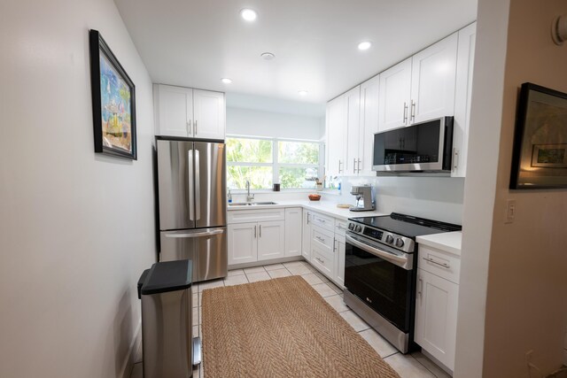 kitchen with sink, light tile patterned flooring, white cabinets, and appliances with stainless steel finishes