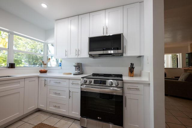 kitchen with stainless steel appliances, light tile patterned flooring, sink, and white cabinets