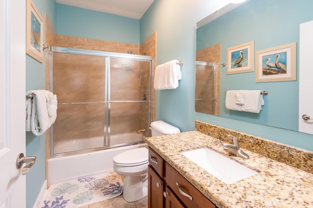 full bathroom with vanity, bath / shower combo with glass door, and toilet