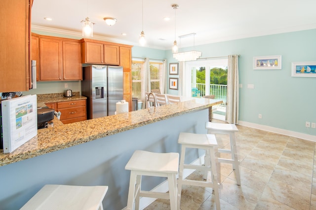 kitchen with ornamental molding, light stone countertops, stainless steel fridge, and decorative light fixtures