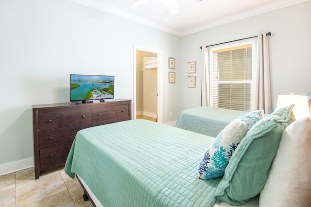 bedroom featuring light tile patterned flooring, ornamental molding, a walk in closet, ceiling fan, and a closet