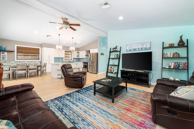 living area with vaulted ceiling with beams, a ceiling fan, visible vents, and light wood-style floors