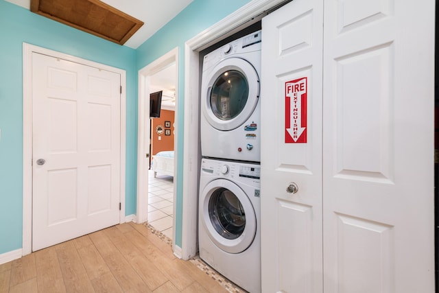 washroom with light wood-style floors, baseboards, laundry area, and stacked washer / drying machine