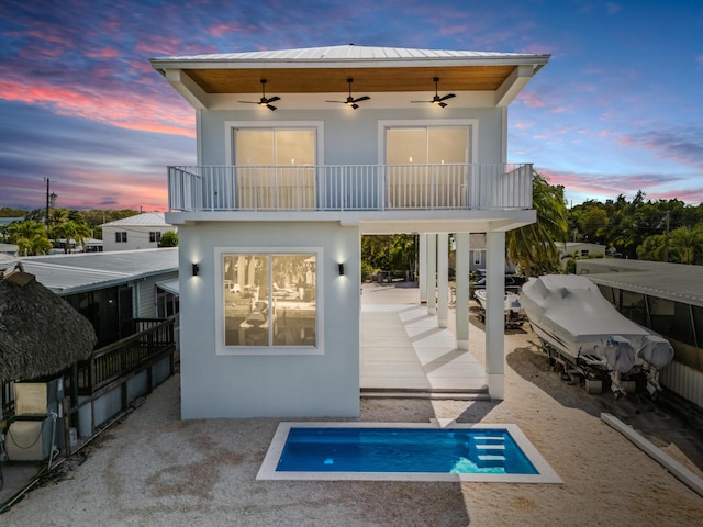 back house at dusk with a patio area, ceiling fan, and a balcony