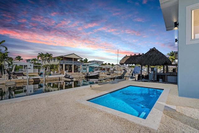 pool at dusk featuring a water view and a gazebo