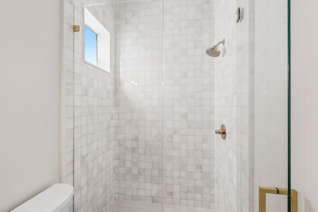 bathroom featuring toilet and tiled shower