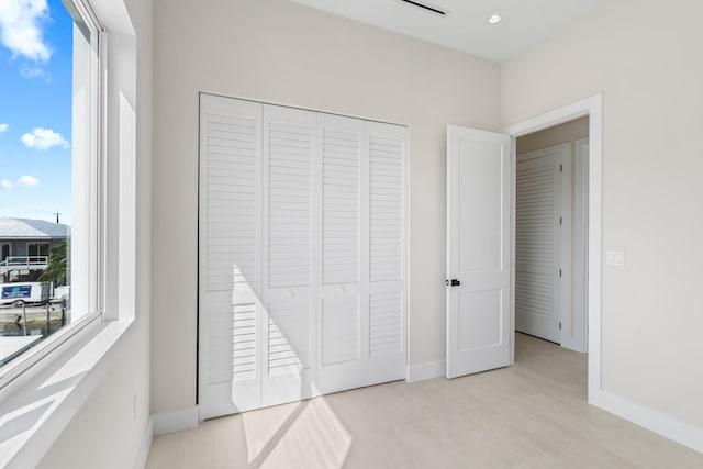 unfurnished bedroom featuring light hardwood / wood-style floors and a closet