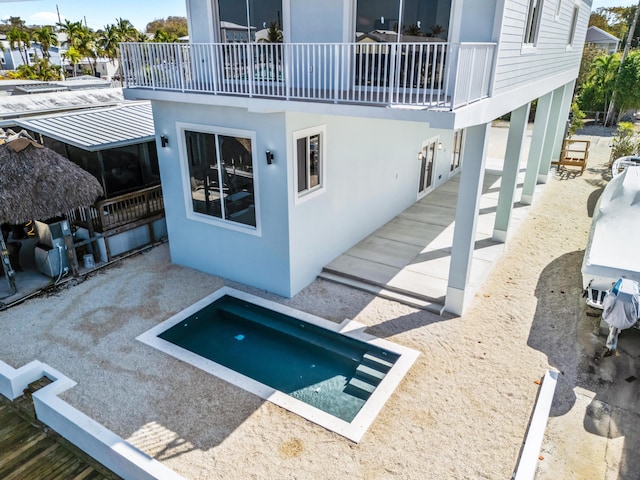 back of property with a pool, a balcony, and a patio area