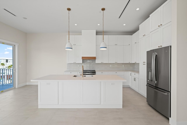 kitchen featuring an island with sink, white cabinets, pendant lighting, sink, and stainless steel fridge with ice dispenser