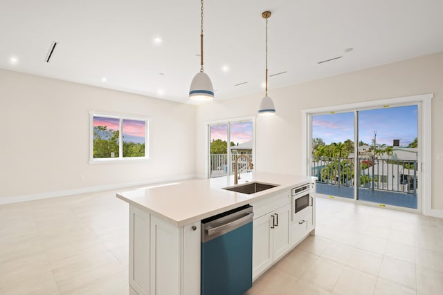 kitchen with a center island with sink, appliances with stainless steel finishes, sink, pendant lighting, and white cabinets