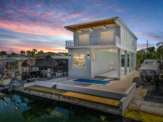 back house at dusk featuring a patio, a balcony, and ceiling fan