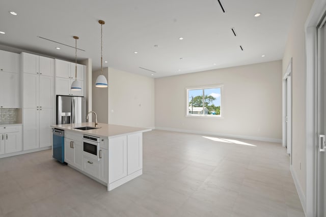 kitchen featuring an island with sink, stainless steel appliances, sink, white cabinets, and pendant lighting