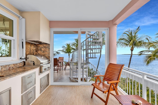 interior space with an outdoor kitchen, stairway, grilling area, and a water view