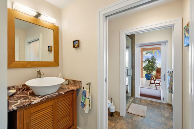 bathroom with toilet, stone finish flooring, a shower stall, and vanity