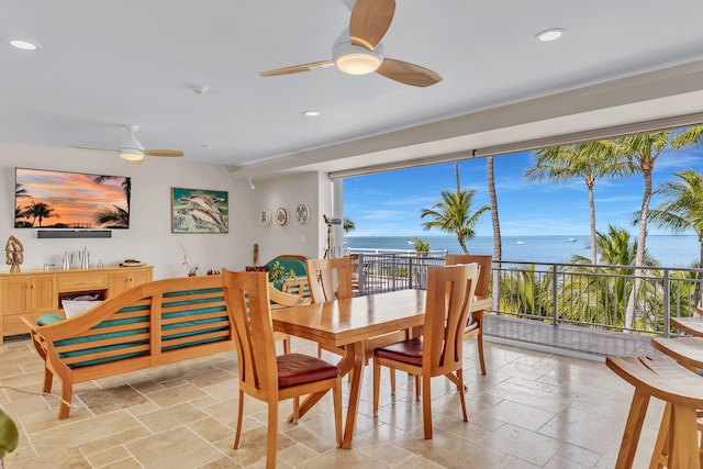 dining area with a water view, stone tile floors, ceiling fan, and recessed lighting