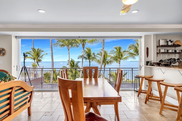 dining room with stone tile flooring, a water view, and a healthy amount of sunlight