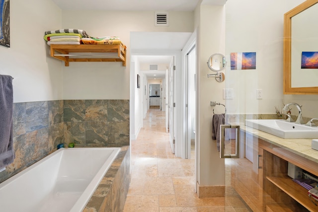 full bath with a bath, vanity, visible vents, and stone tile floors