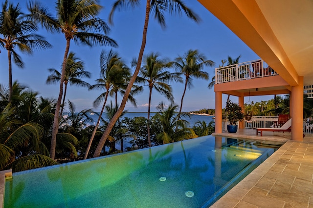 pool at dusk featuring a hot tub