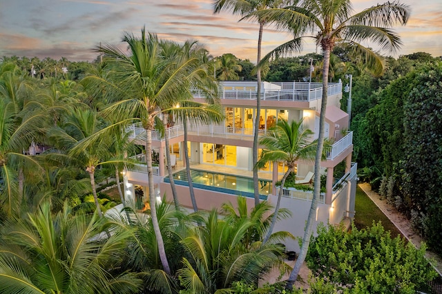 100 List St, Islamorada, FL 33036 - property exterior at dusk featuring a balcony, an outdoor pool, stairway, a patio area, and stucco siding