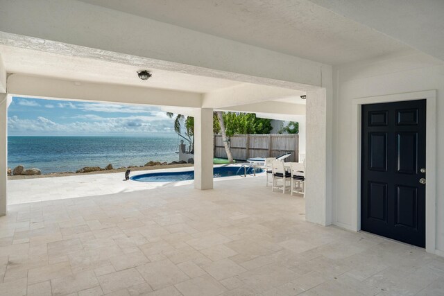 view of swimming pool featuring a water view and a patio