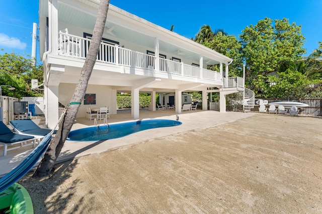 back of property featuring a balcony, a fenced in pool, and a patio area