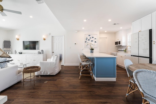 kitchen with a kitchen breakfast bar, dark wood-type flooring, white cabinets, and white appliances