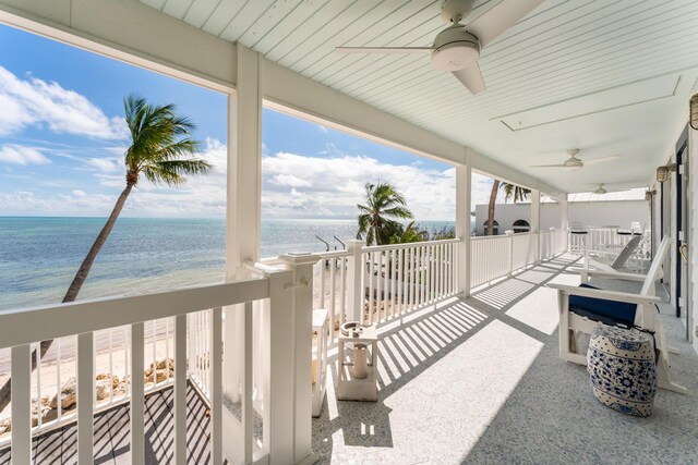 view of patio / terrace featuring a balcony, a beach view, ceiling fan, and a water view