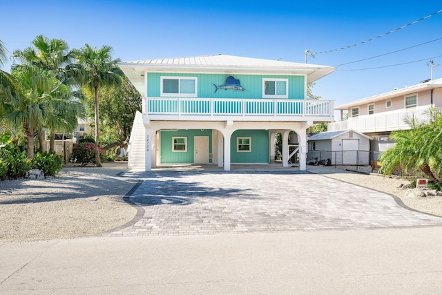 22738 Blackbeard Ln, Cudjoe, FL 33042 - raised beach house featuring a carport, decorative driveway, stairway, and metal roof