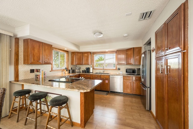 22738 Blackbeard Ln, Cudjoe, FL 33042 - kitchen featuring appliances with stainless steel finishes, a peninsula, a sink, backsplash, and a breakfast bar area