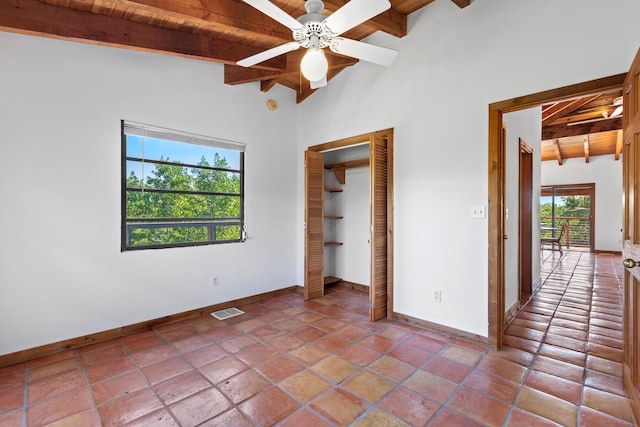 unfurnished bedroom with ceiling fan, vaulted ceiling with beams, wood ceiling, and a closet