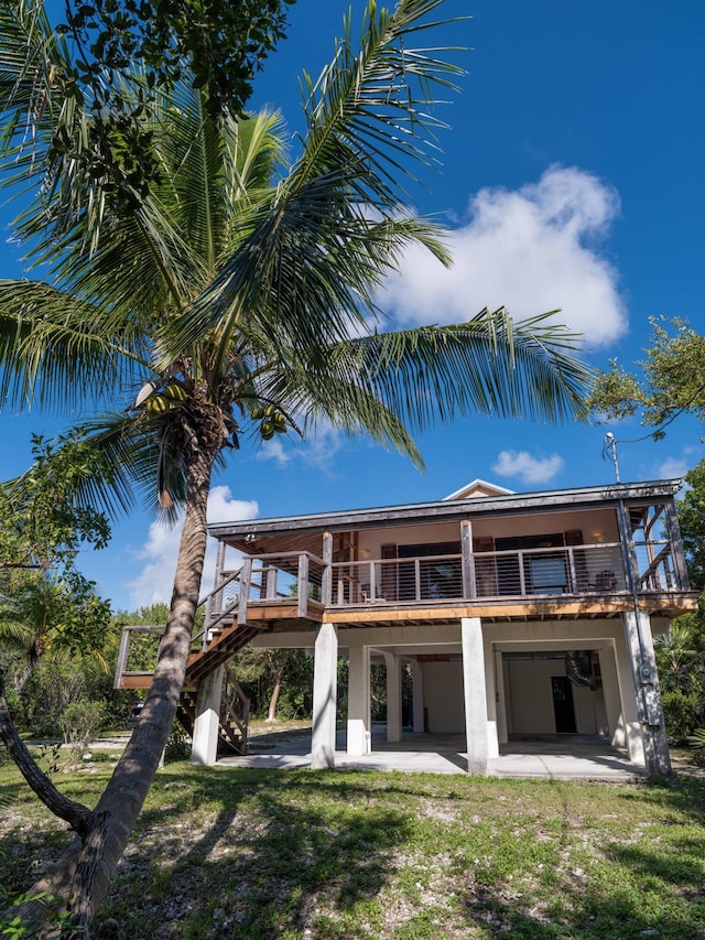 rear view of property featuring a patio, a balcony, and a yard