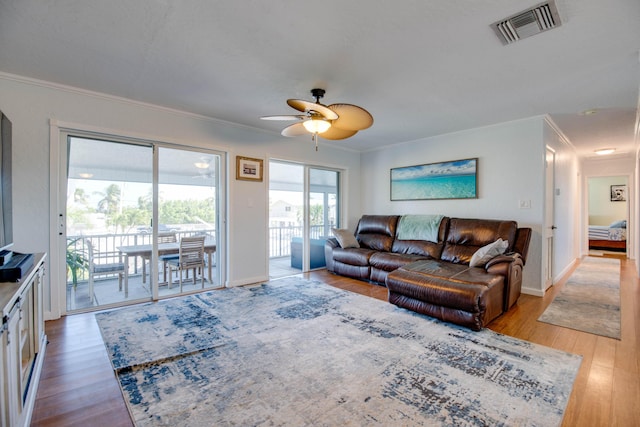 living area with visible vents, baseboards, ceiling fan, ornamental molding, and light wood-style floors