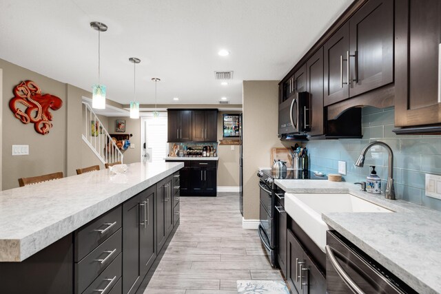 kitchen featuring a breakfast bar, hanging light fixtures, dark brown cabinets, appliances with stainless steel finishes, and decorative backsplash