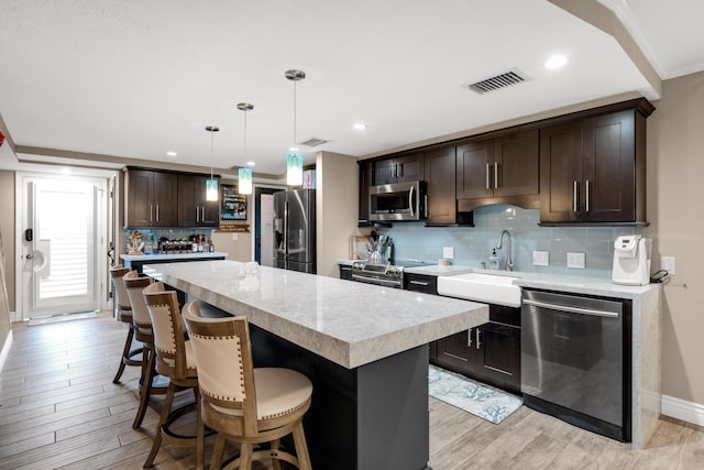 kitchen with sink, hanging light fixtures, a center island, stainless steel appliances, and dark brown cabinets