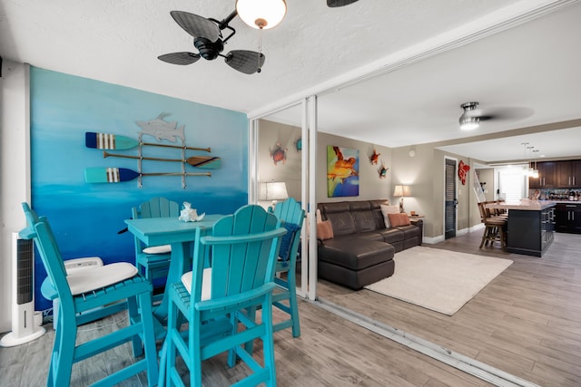 dining area with a textured ceiling, ceiling fan, and light hardwood / wood-style floors