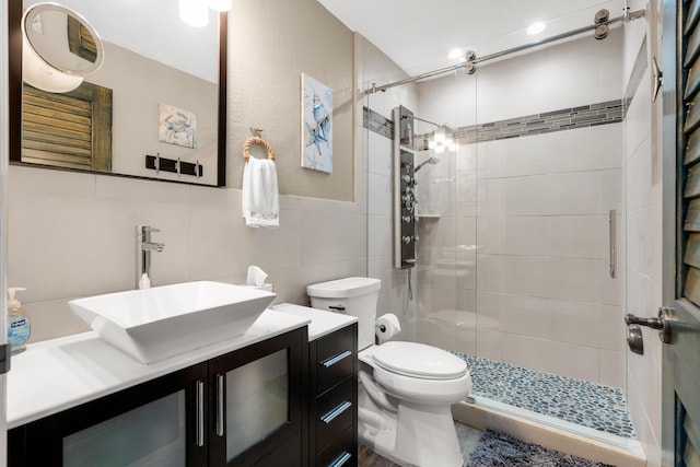 bathroom featuring vanity, a shower with shower door, tile walls, and toilet