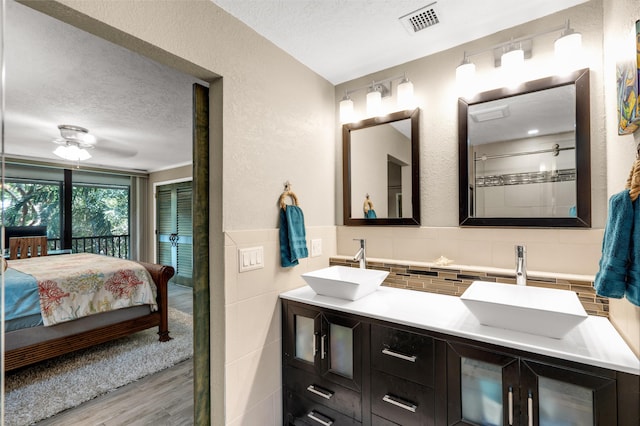 bathroom featuring wood-type flooring, tile walls, vanity, and a textured ceiling