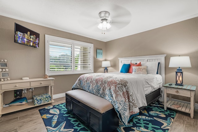 bedroom with hardwood / wood-style floors, ornamental molding, and ceiling fan