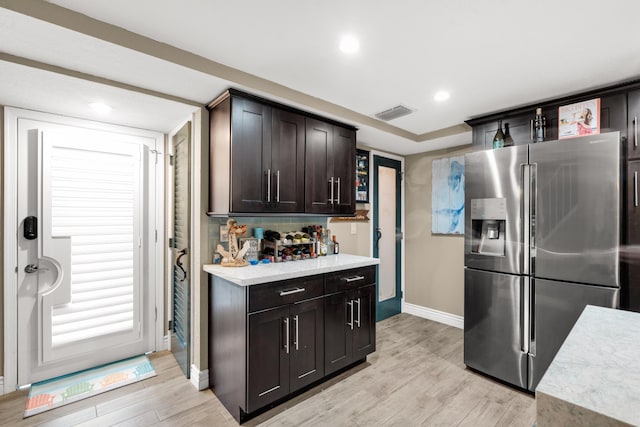 kitchen with stainless steel refrigerator with ice dispenser, dark brown cabinets, and light hardwood / wood-style flooring