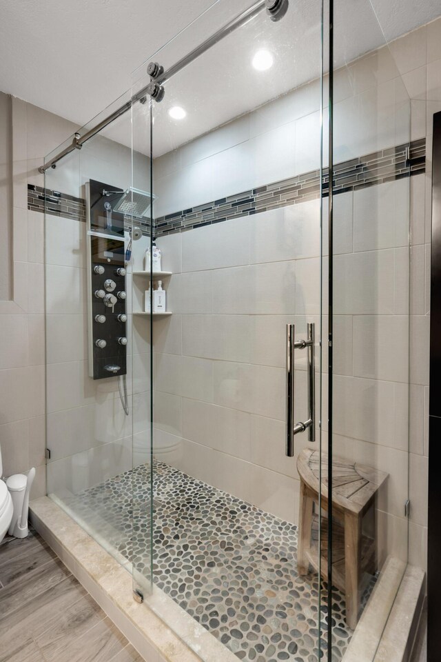 bathroom with toilet, an enclosed shower, and hardwood / wood-style floors