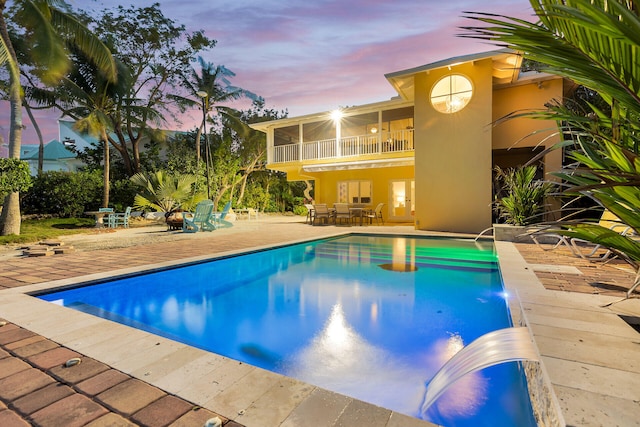 pool at dusk featuring a patio