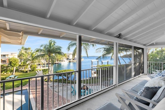 sunroom / solarium featuring a water view and lofted ceiling with beams