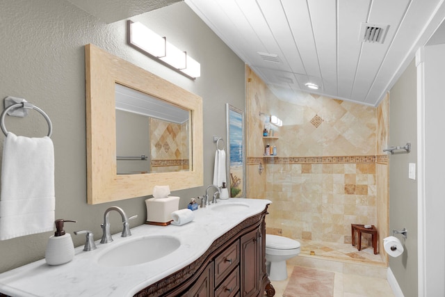 bathroom featuring a tile shower, vanity, and toilet