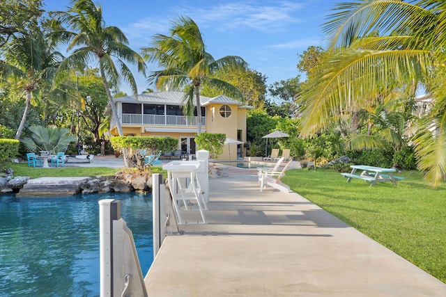 dock area featuring a lawn, a patio, a balcony, and a water view