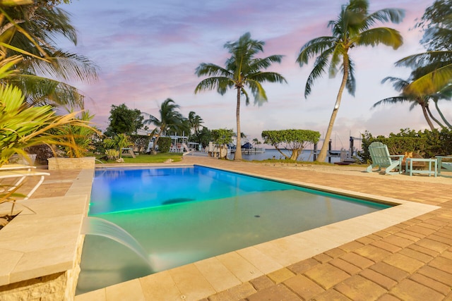 pool at dusk with a patio area