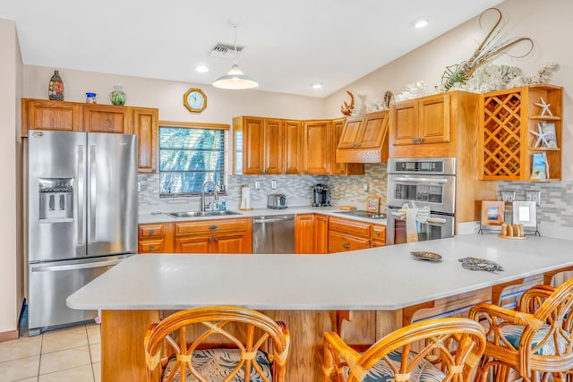 kitchen featuring a breakfast bar, sink, decorative light fixtures, light tile patterned floors, and appliances with stainless steel finishes