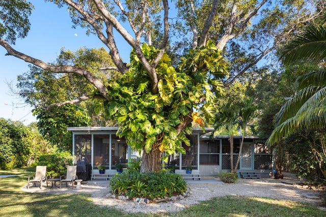 rear view of house with a sunroom and a lawn