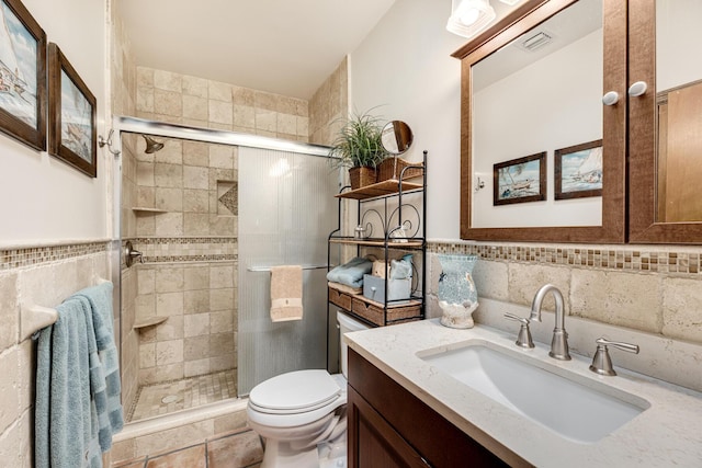 full bath with tile walls, visible vents, toilet, a shower stall, and vanity