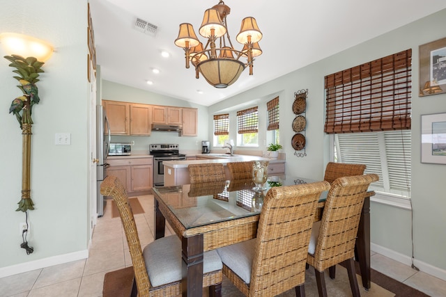 dining space with lofted ceiling, sink, light tile patterned floors, and a notable chandelier