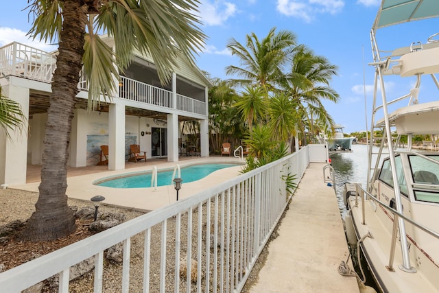 view of swimming pool featuring a water view, a patio area, and a sunroom